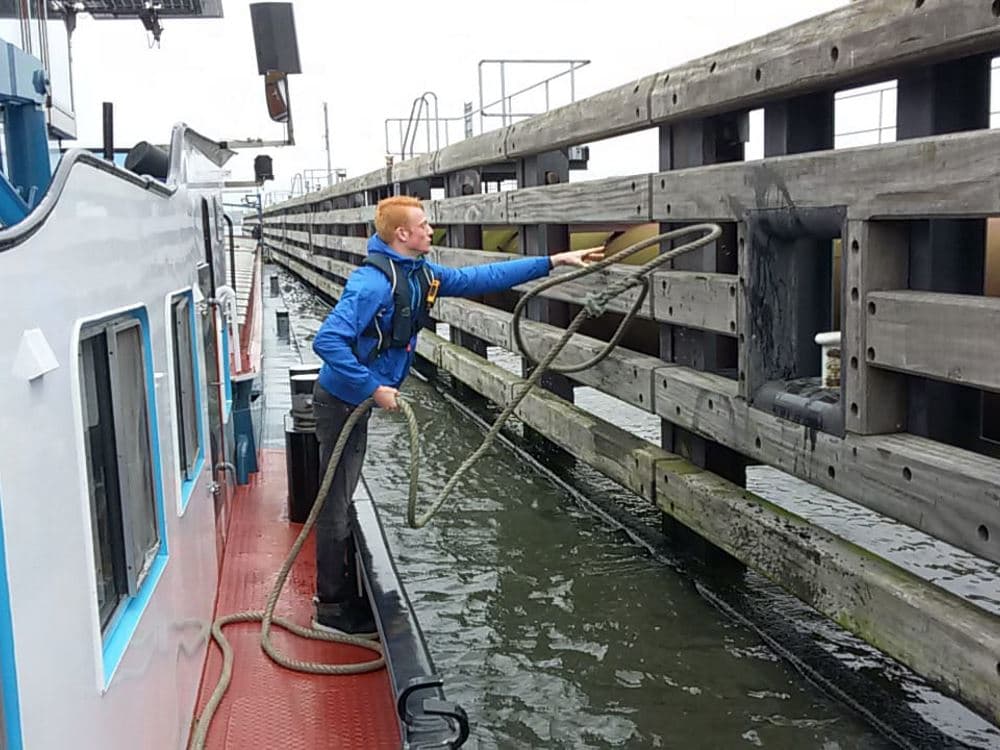 Matroos gooit een tros naar de sluiswand