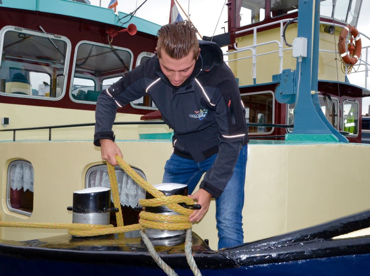 Matroos legt de trossen vast op dek